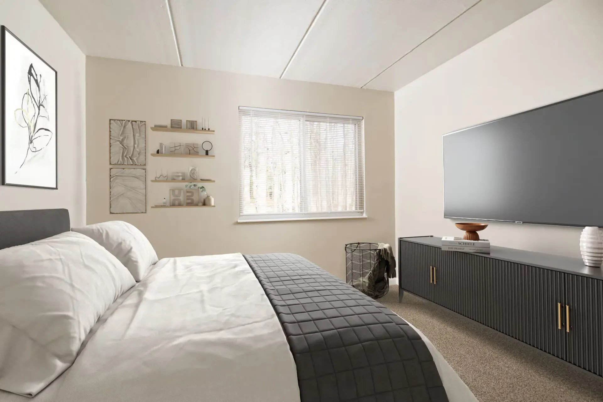 Bedroom in a modern apartment with a large bed, wall art, shelves, and a TV on a console at Westover Pointe in Wilmington, DE.