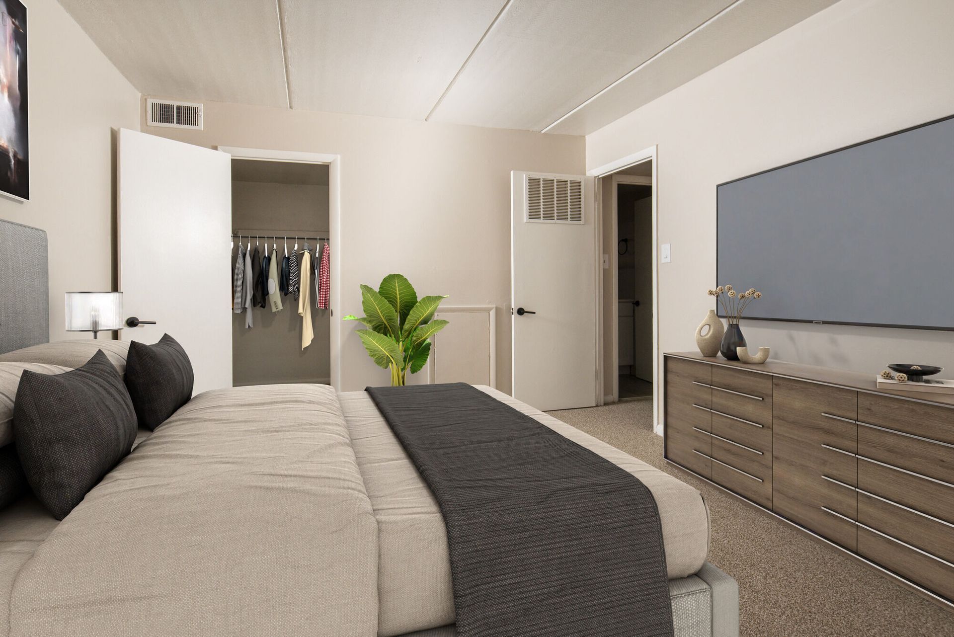 Bedroom in an apartment with a bed, dresser, large TV, and open closet at Westover Pointe in Wilmington, DE.