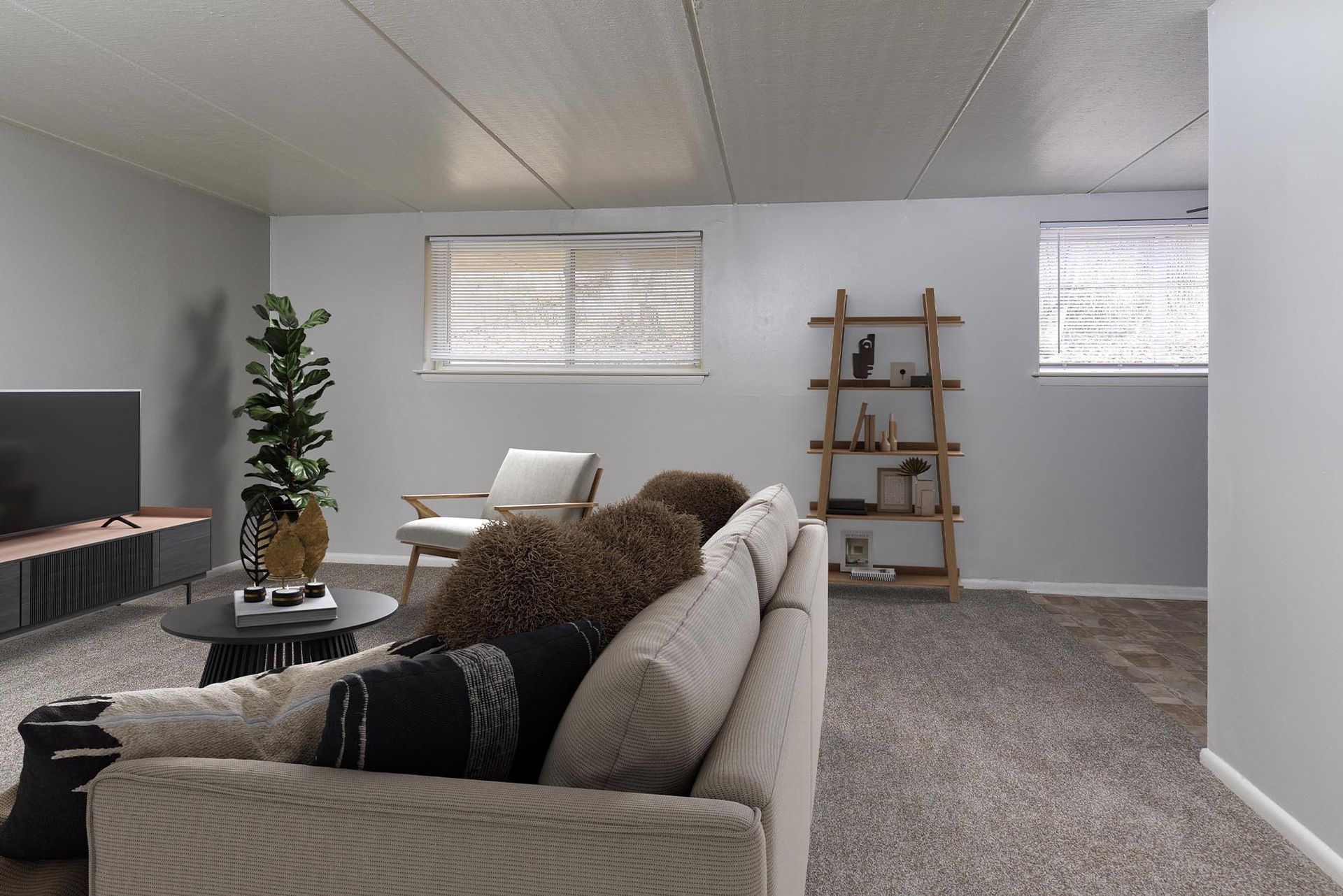 Cozy living room with beige sofa, round black coffee table, TV console, plant, and ladder-style bookshelf at Westover Pointe in Wilmington, DE.