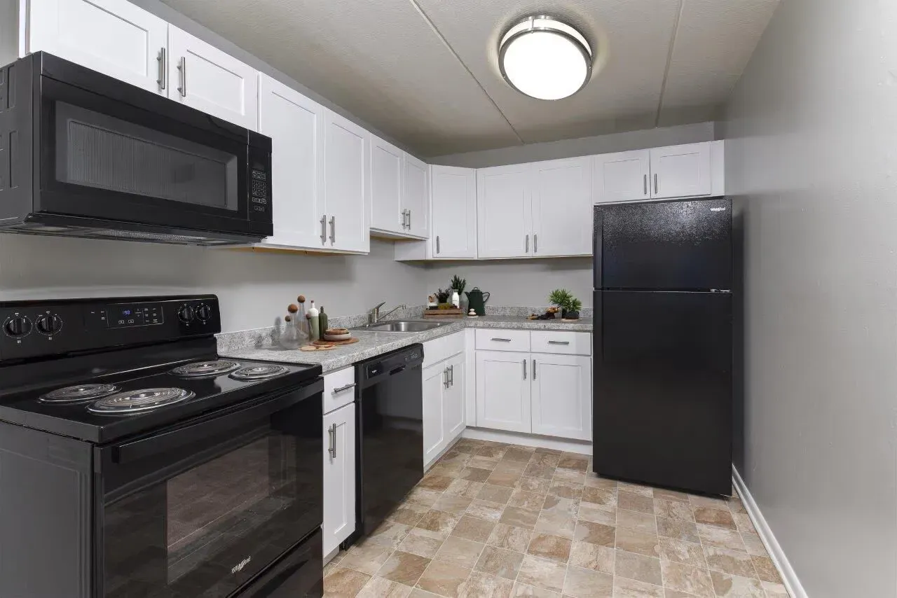 Kitchen with white cabinets, gray countertops, and black appliances at Westover Pointe in Wilmington, DE.