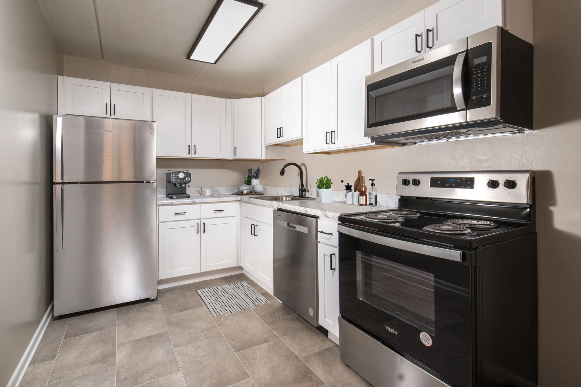 Modern kitchen with white cabinets and stainless steel appliances (fridge, oven, microwave) and a dishwasher at Westover Pointe in Wilmington, DE.
