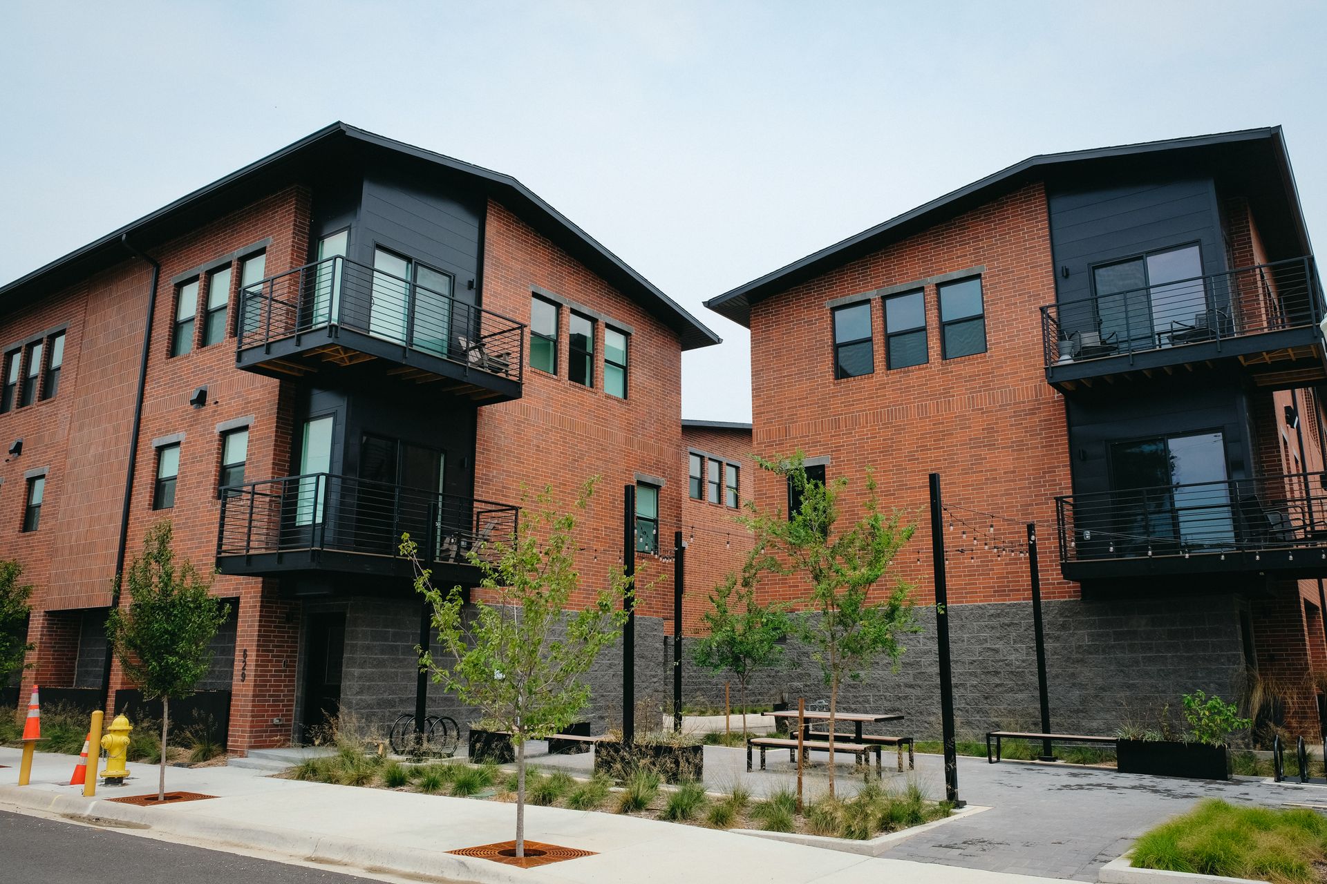 A row of brick buildings with balconies and a fire hydrant in front of them.