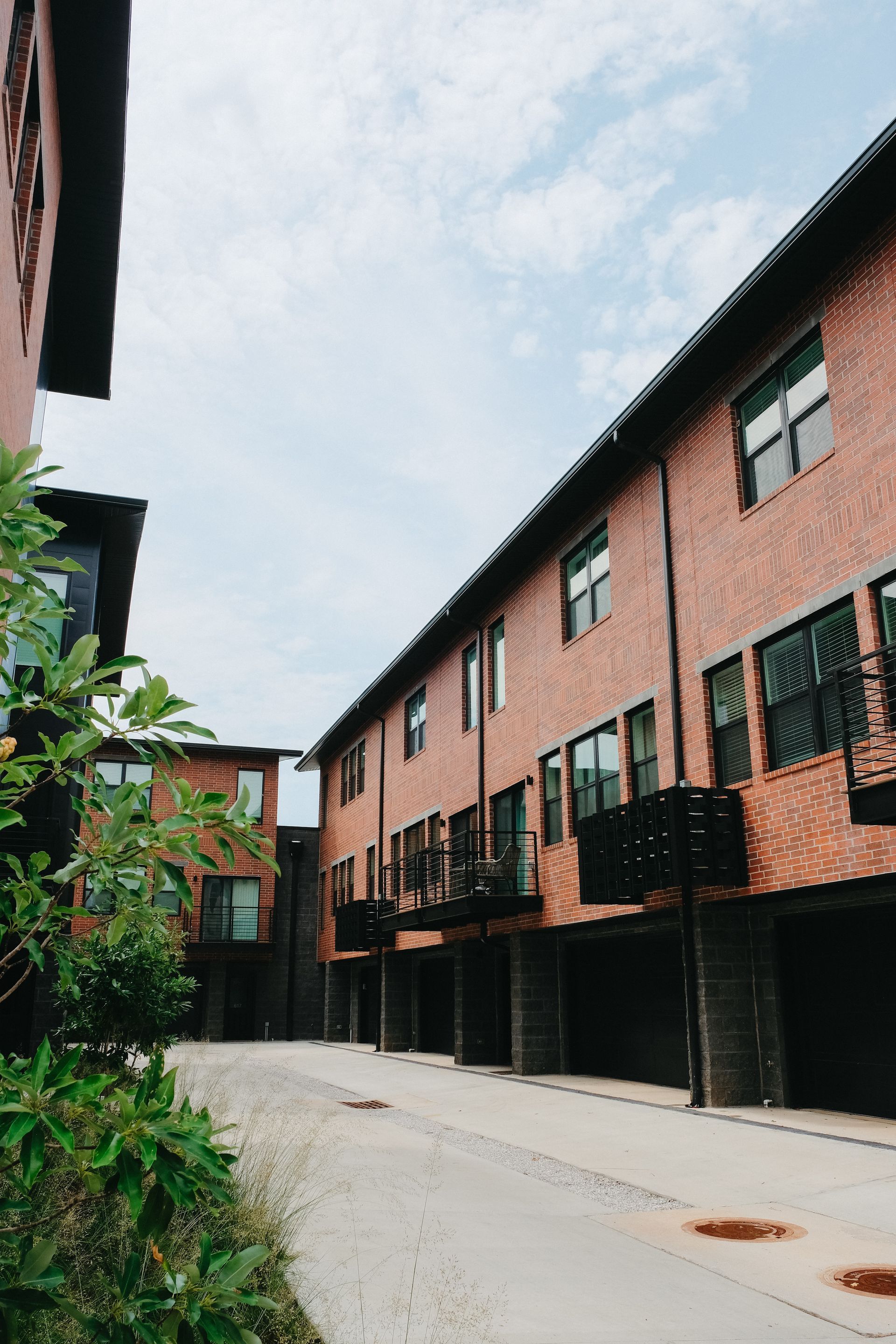A row of brick buildings with balconies and garages on a sunny day.