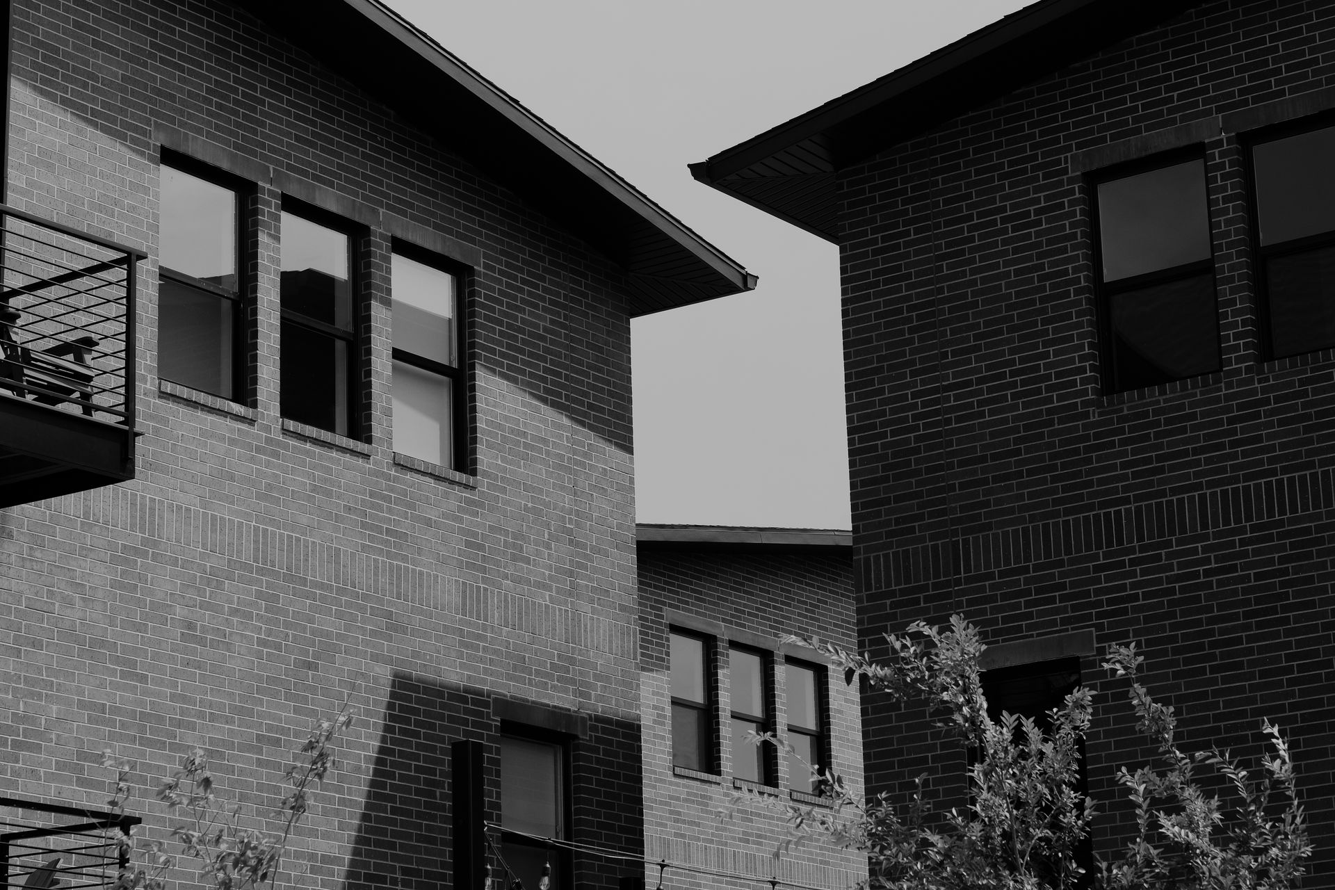 A black and white photo of two brick buildings with balconies