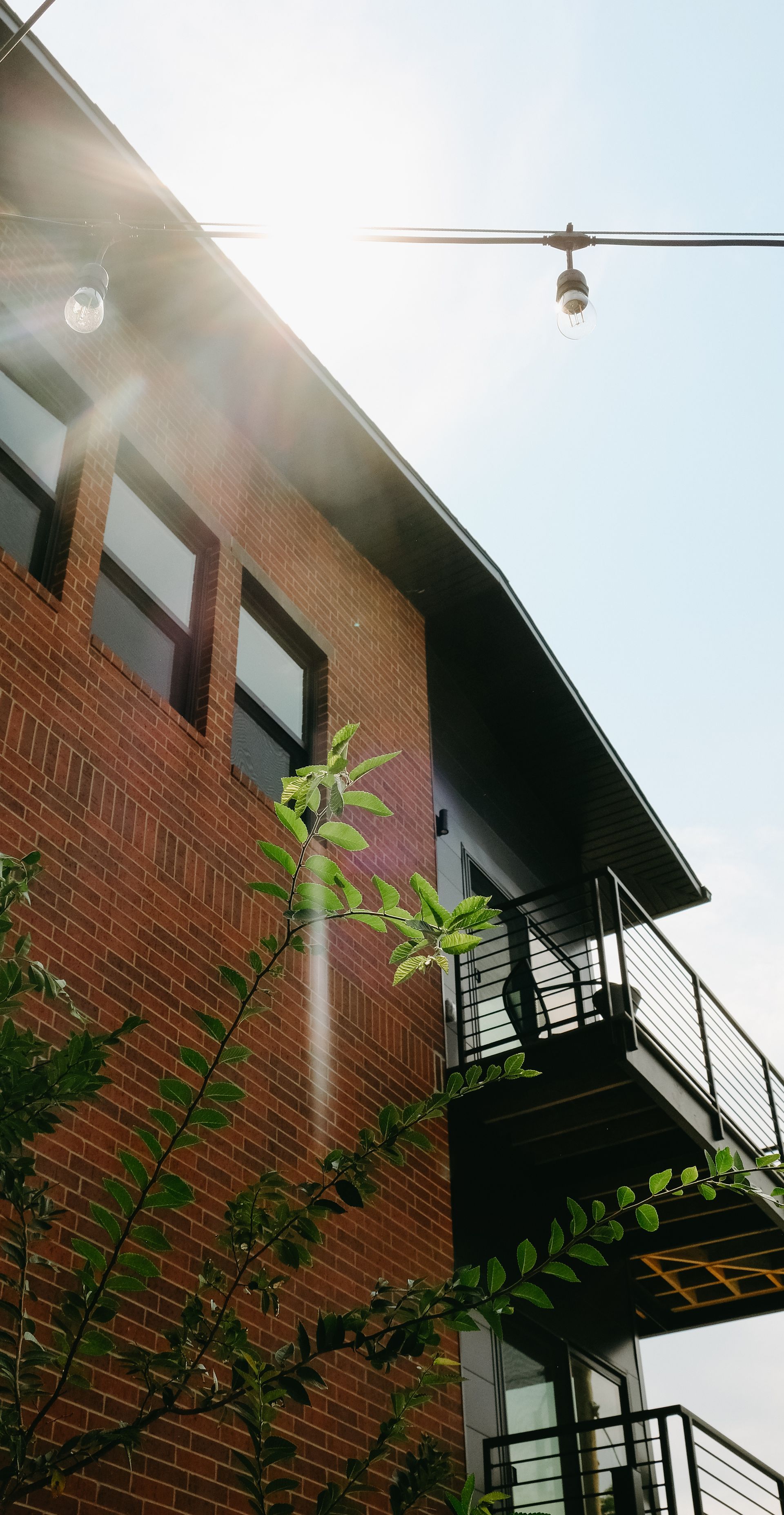The sun is shining through the windows of a brick building with a balcony.