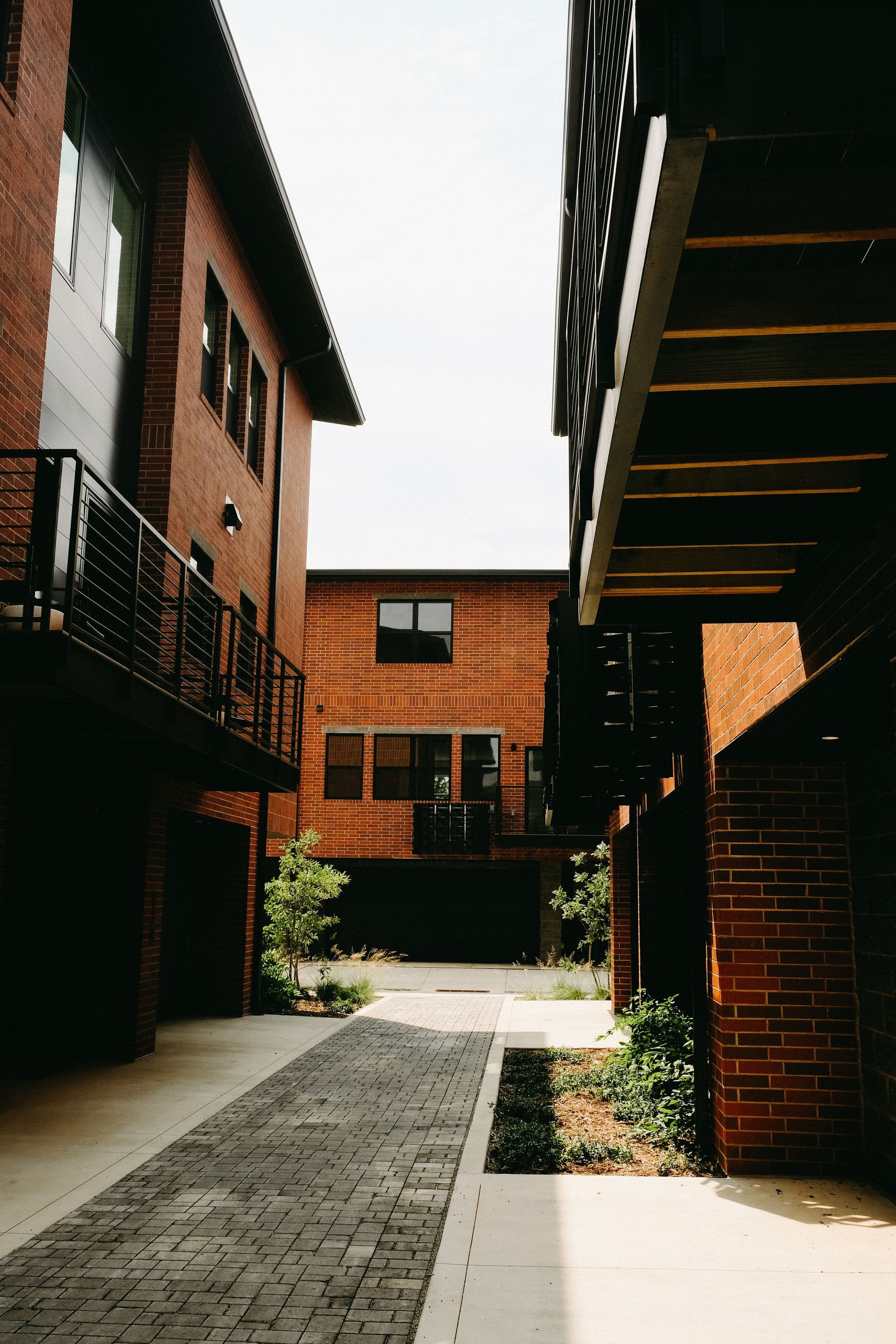 A narrow alleyway between two brick buildings with balconies and stairs.