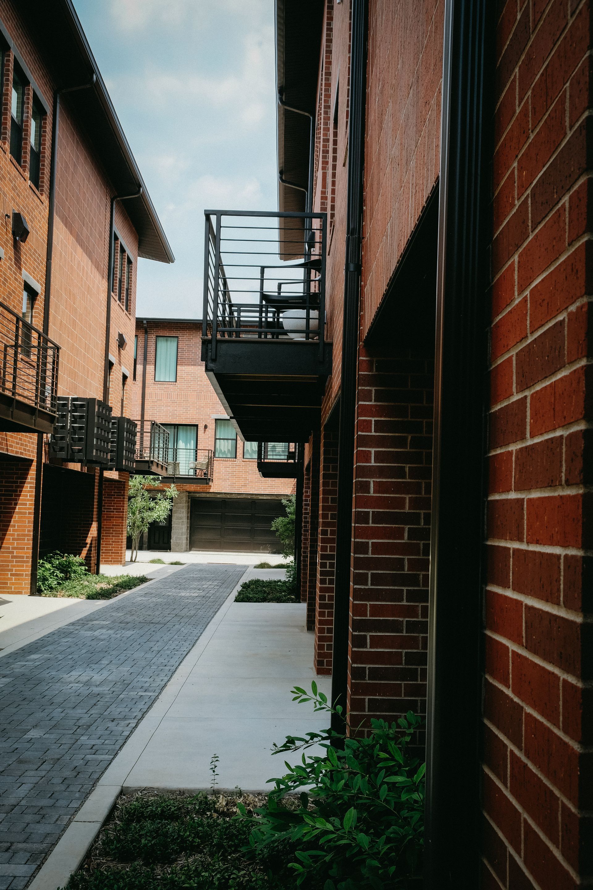 A narrow alleyway between two brick buildings with a balcony.