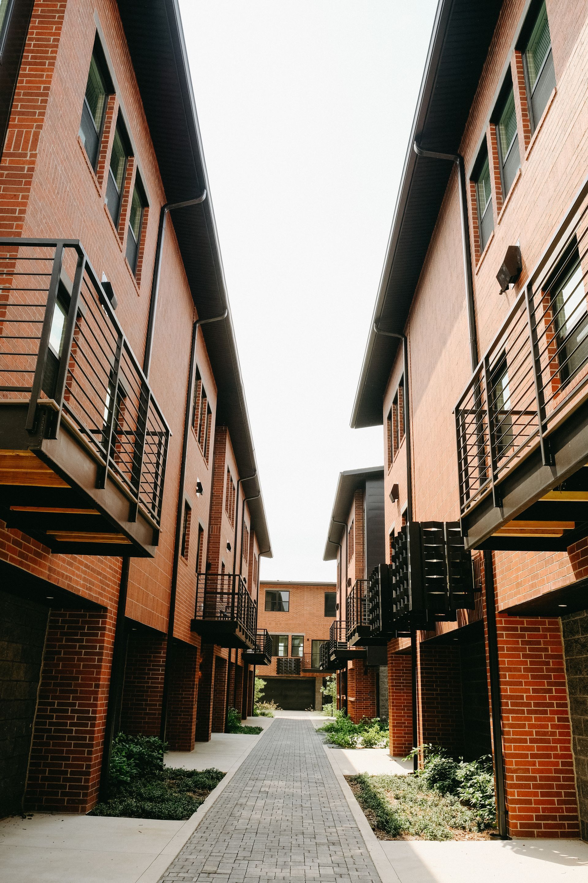 A narrow alleyway between two brick buildings with balconies.