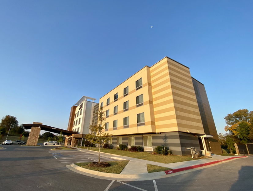 A large building with a lot of windows is next to a parking lot.