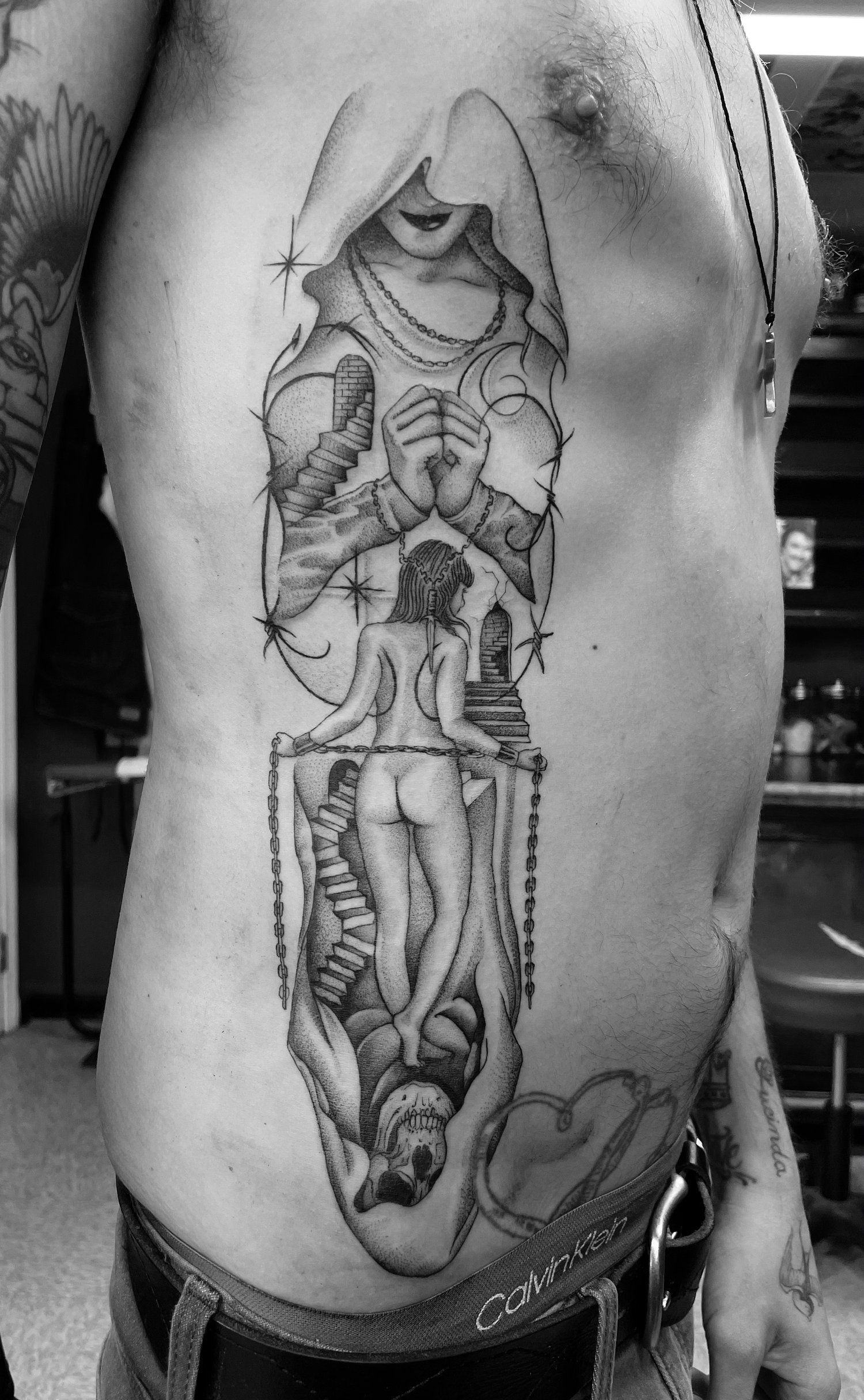 A black and white photo of a man with a tattoo on his side.