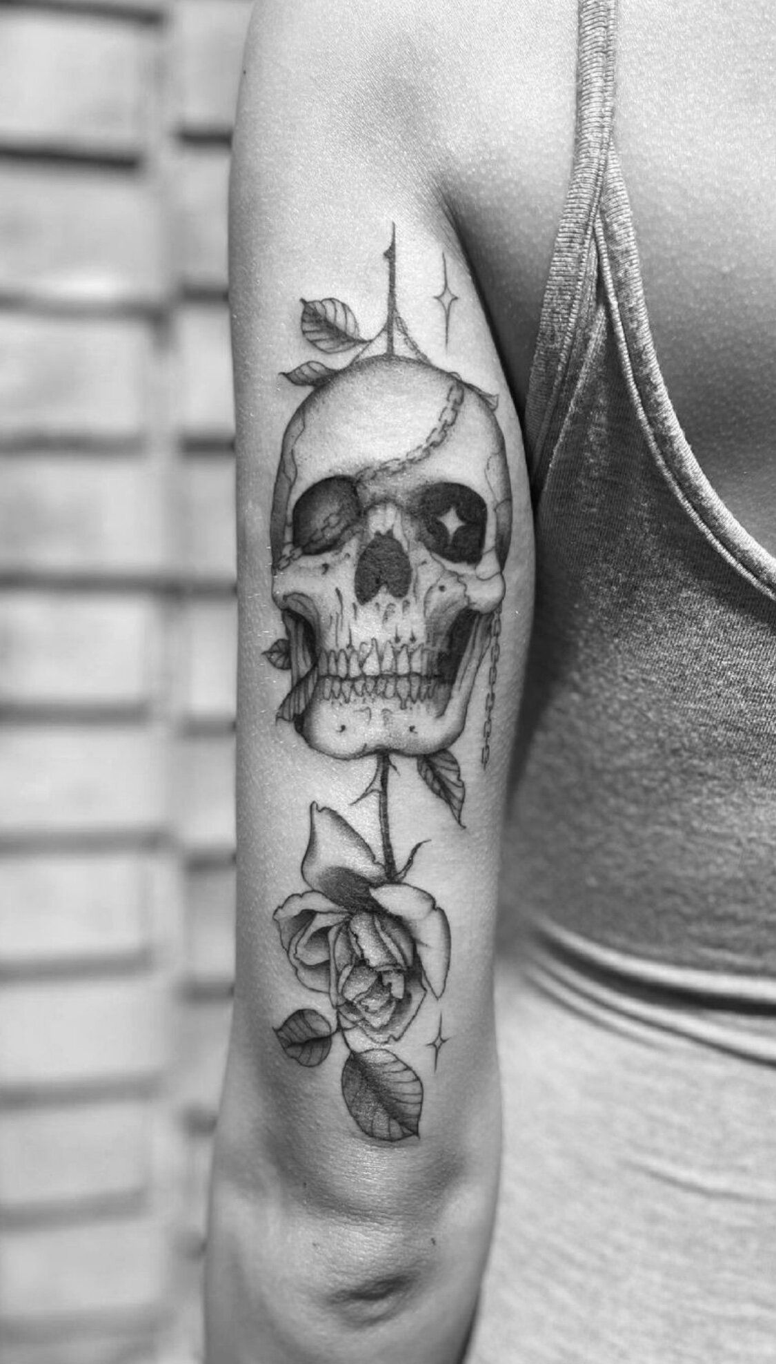 A woman has a tattoo of a skull and roses on her arm.