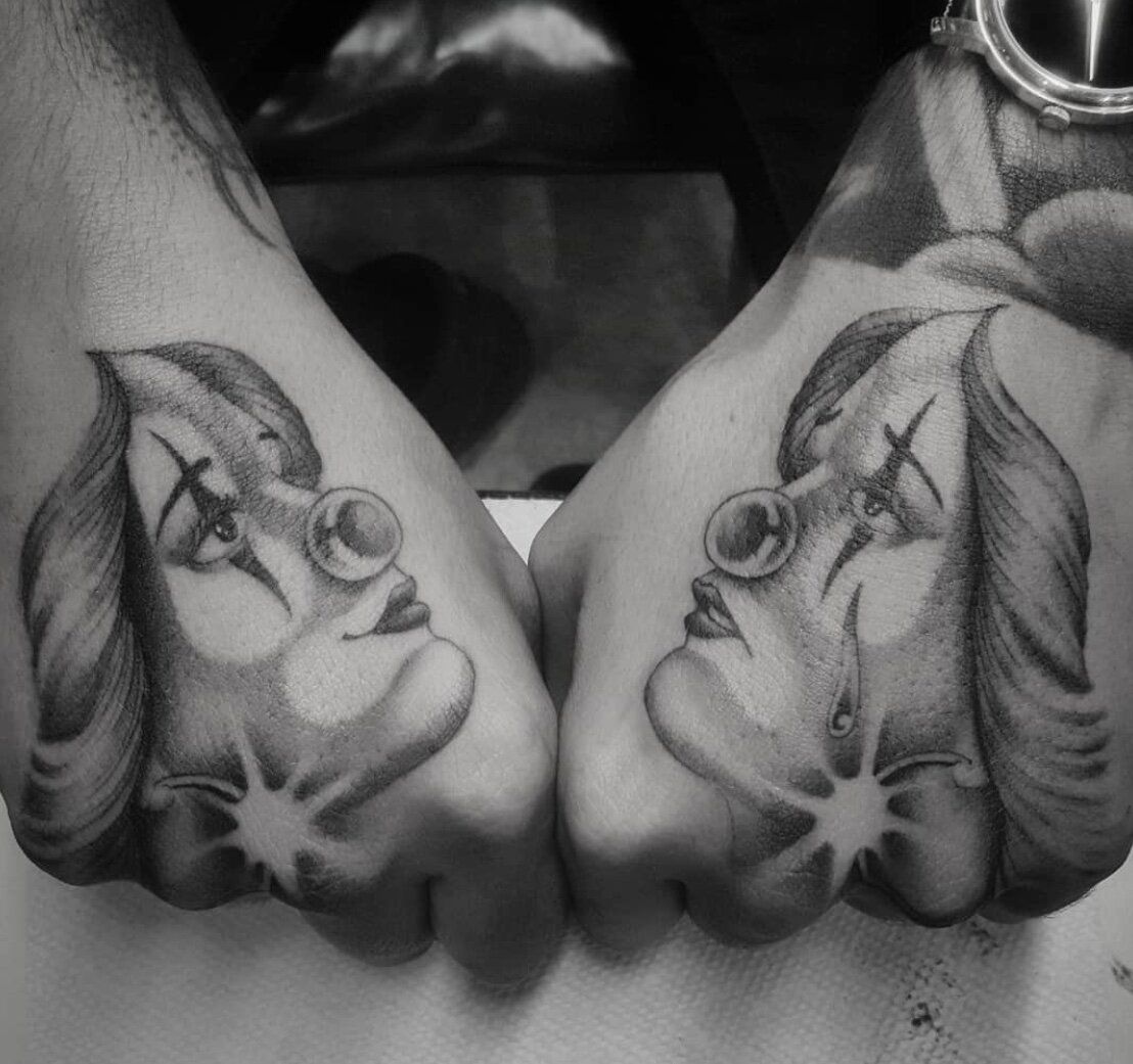 A black and white photo of a person with two tattoos on their hands