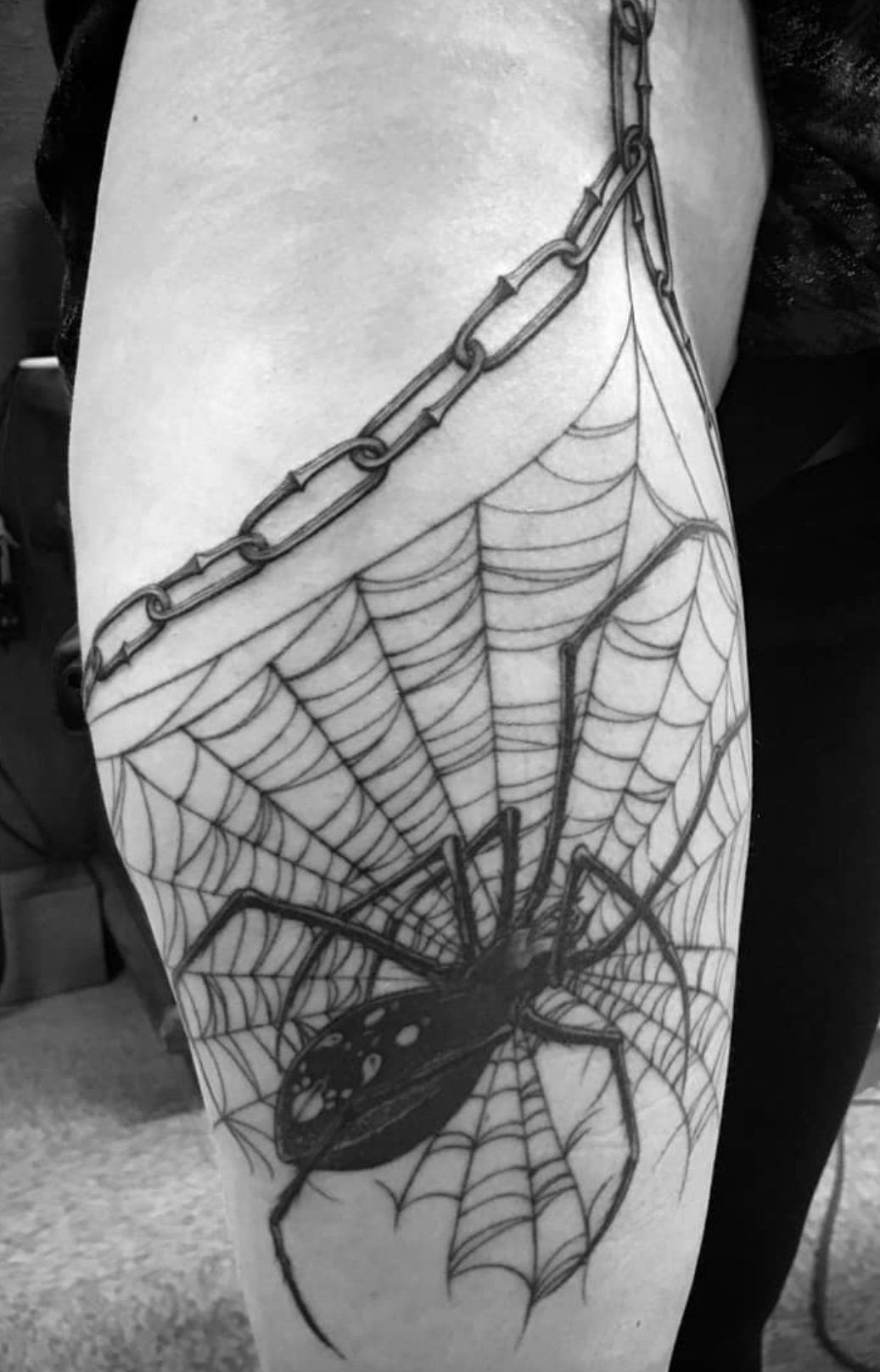 A black and white photo of a spider web tattoo on a person 's leg