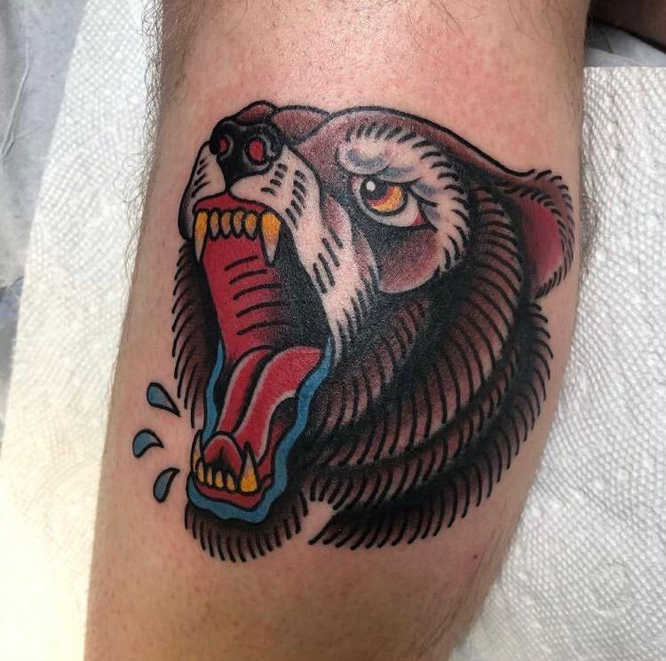 A person has a tattoo of a bear on their leg