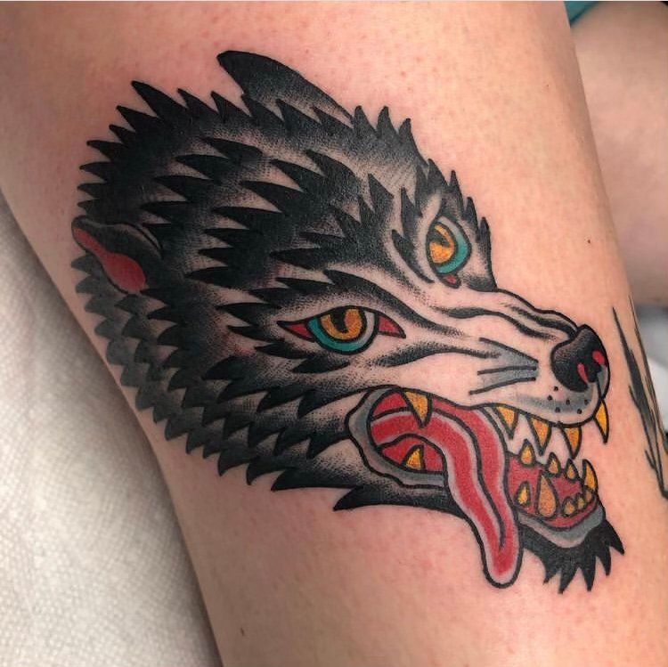 A tattoo of a wolf 's head with its tongue hanging out