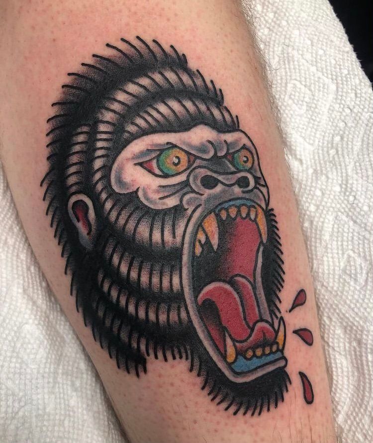A tattoo of a gorilla with its mouth open on a person 's arm.