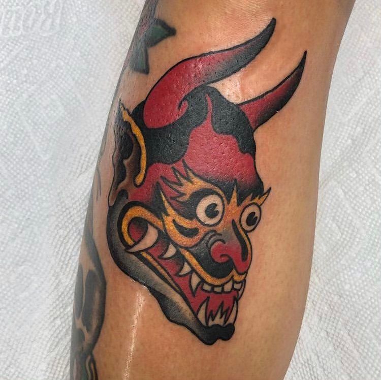 A tattoo of a devil 's head on a person 's leg