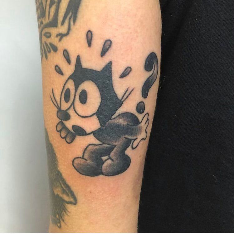 A person has a tattoo of felix the cat on their arm