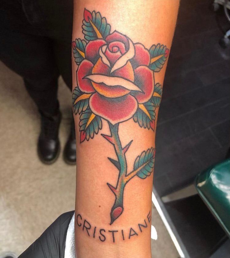 A person has a tattoo of a rose and the name cristiano on their arm