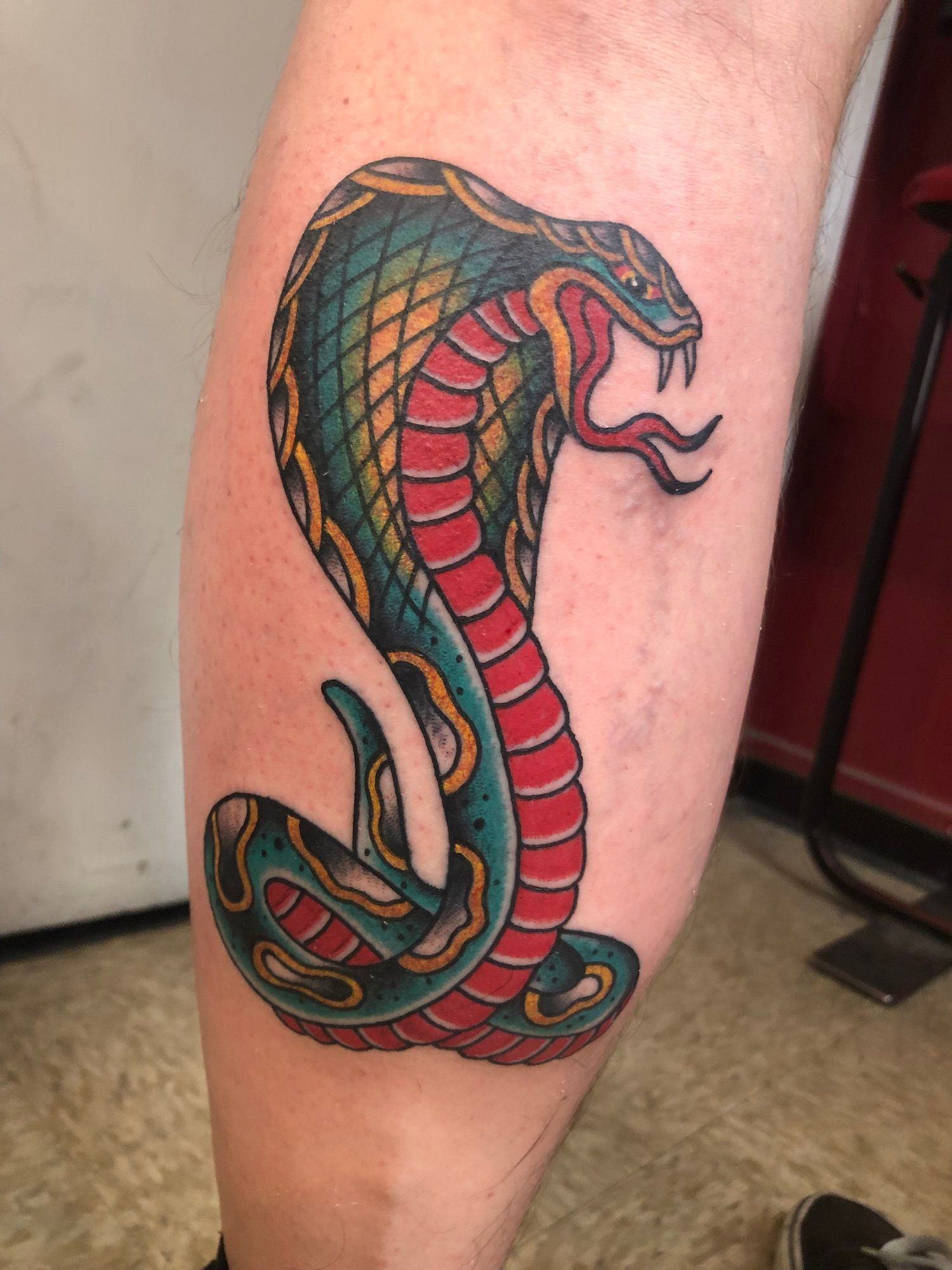 A person has a tattoo of a cobra on their leg