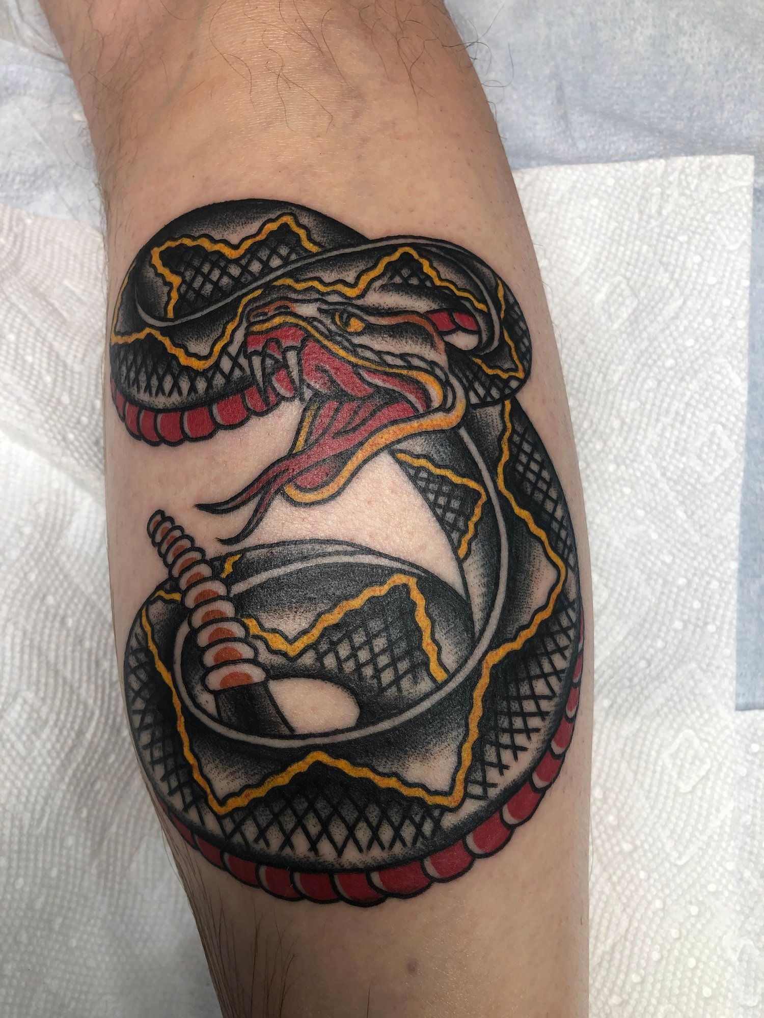 A person has a tattoo of a rattlesnake on their leg.