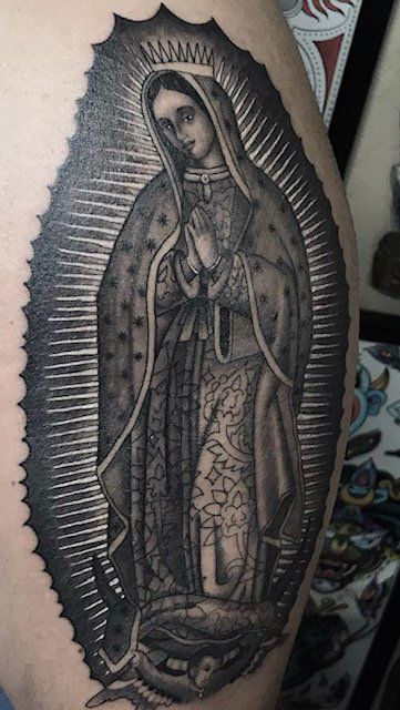 A woman has a tattoo of the virgin mary on her arm