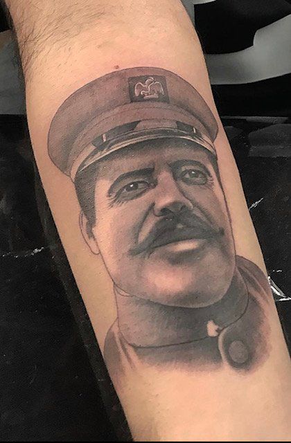 A man has a tattoo of a man in a military uniform on his arm.