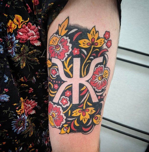 A man has a tattoo of the letter k on his arm