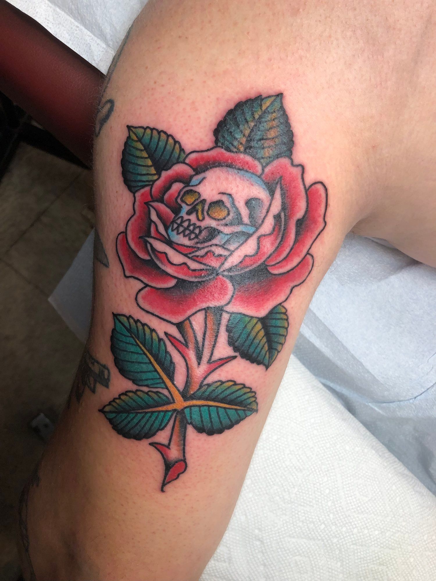 A person has a tattoo of a rose with a skull in it
