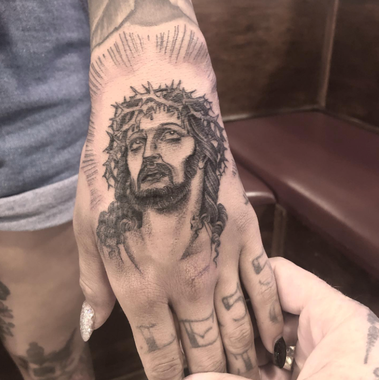 A person has a tattoo of jesus on their hand