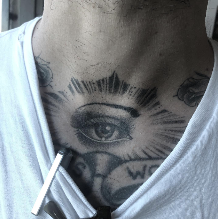 A man has a tattoo of an eye on his chest