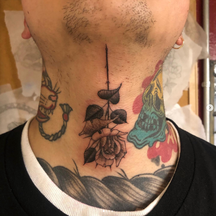 A man has a tattoo of a rose on his neck