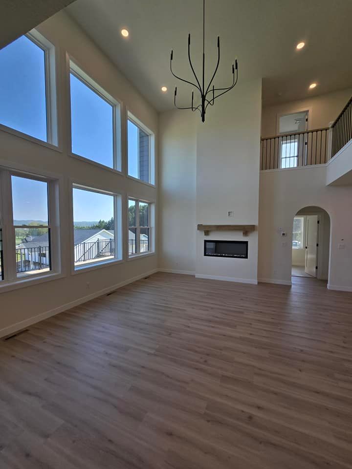 An empty living room with lots of windows and a fireplace.