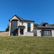 A large house is sitting on top of a lush green field.