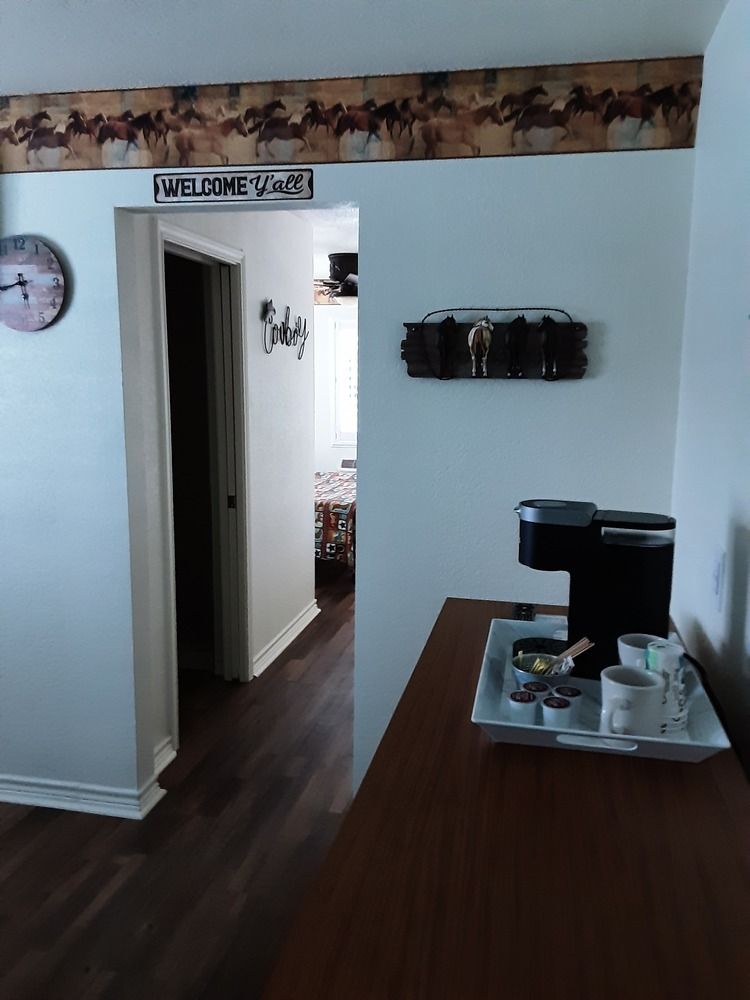 Interior view: Coffee station on a table, hallway with horse decor, and a clock on the wall.