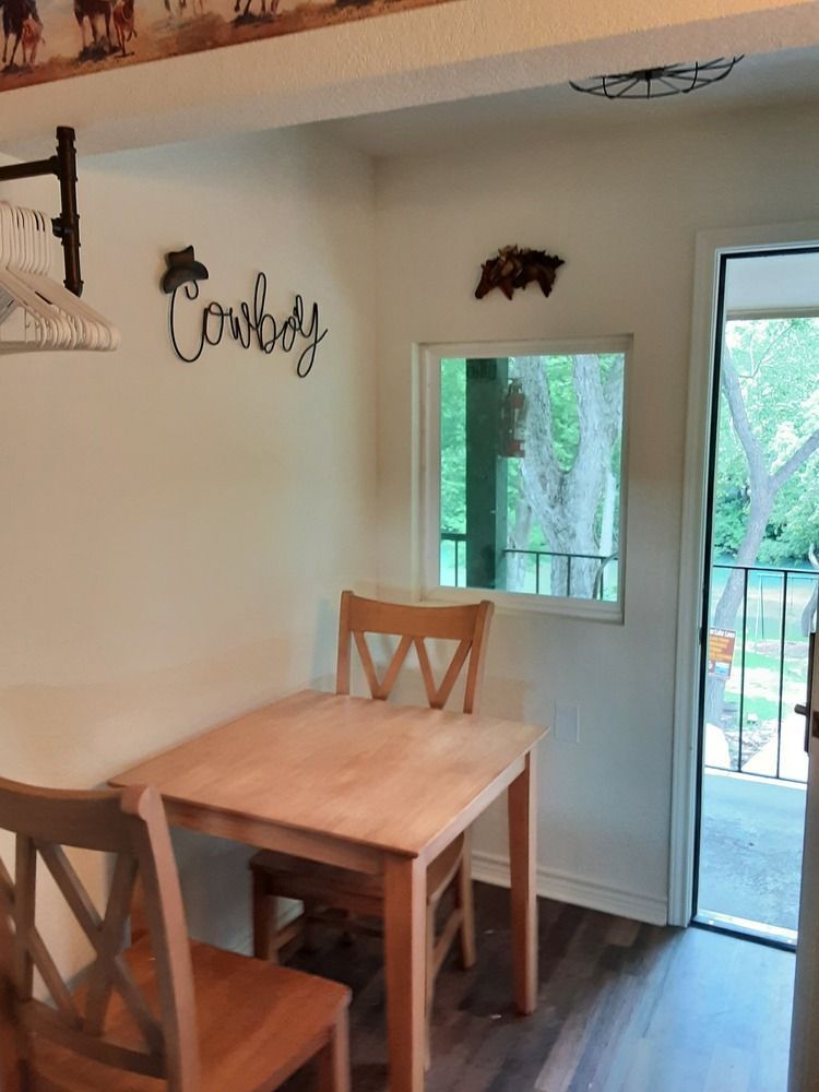 A small dining area with a wooden table and chairs, a window, and a door leading outside.