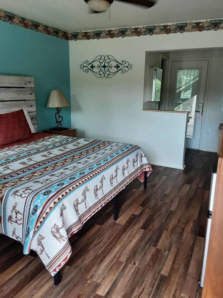Bedroom with bed, turquoise wall, wooden floor, decorative trim, and door.