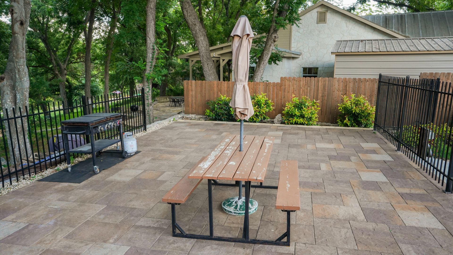 Patio with picnic table and umbrella, grill, and fenced yard.