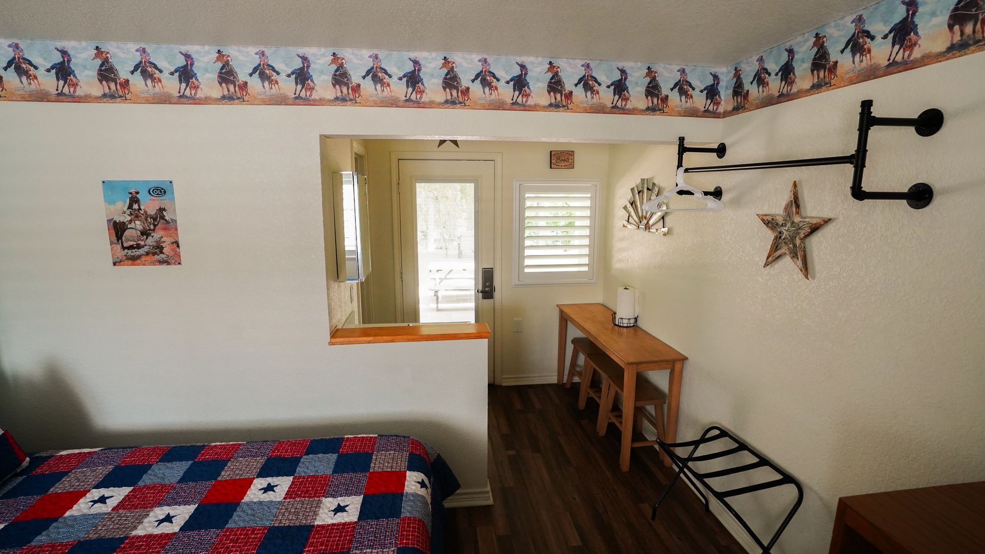 Bedroom with a bed, desk, and doorway with a cowboy-themed border.