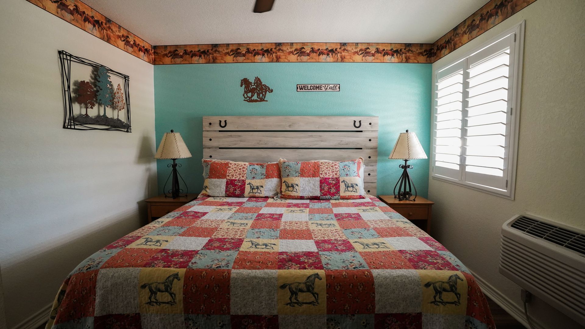 Bedroom with a patchwork quilt, turquoise wall, and wooden headboard.