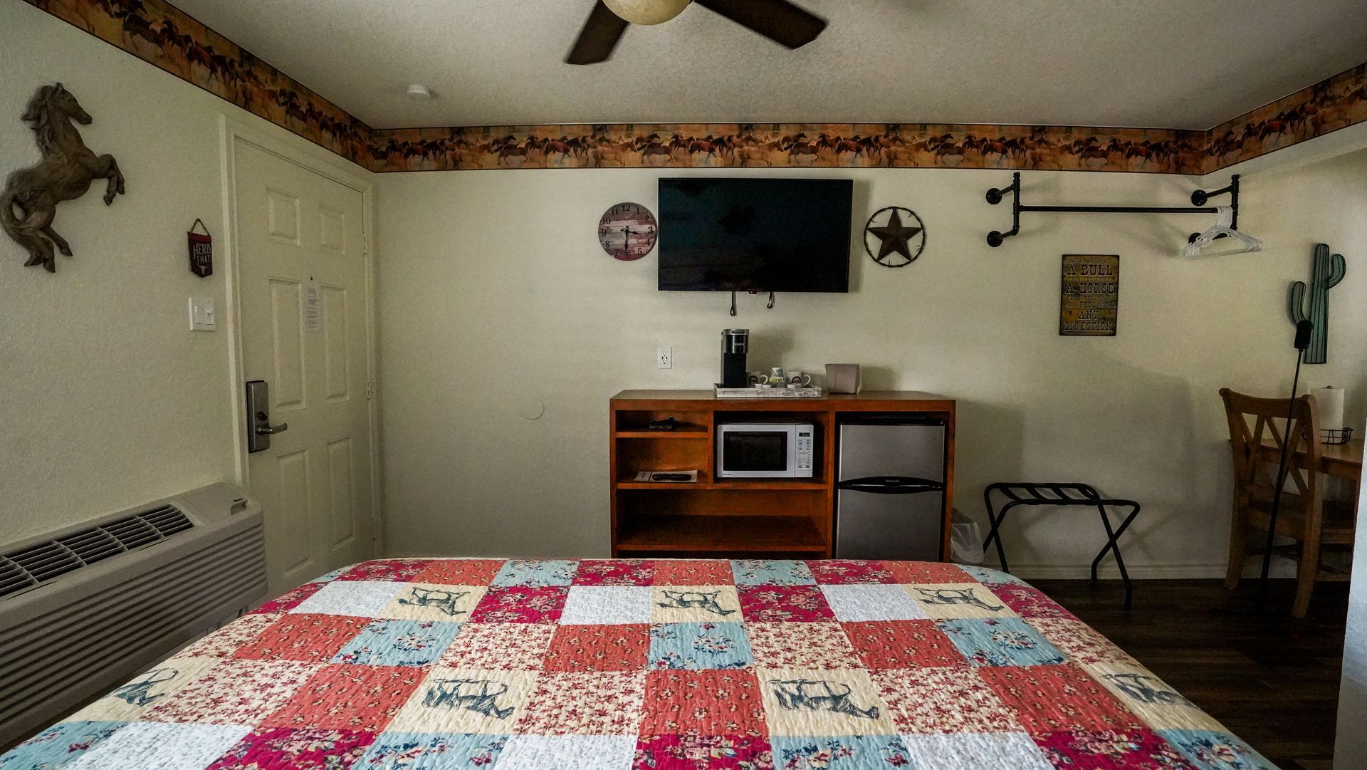 Hotel room with a bed, TV, microwave, and Western-themed decor.
