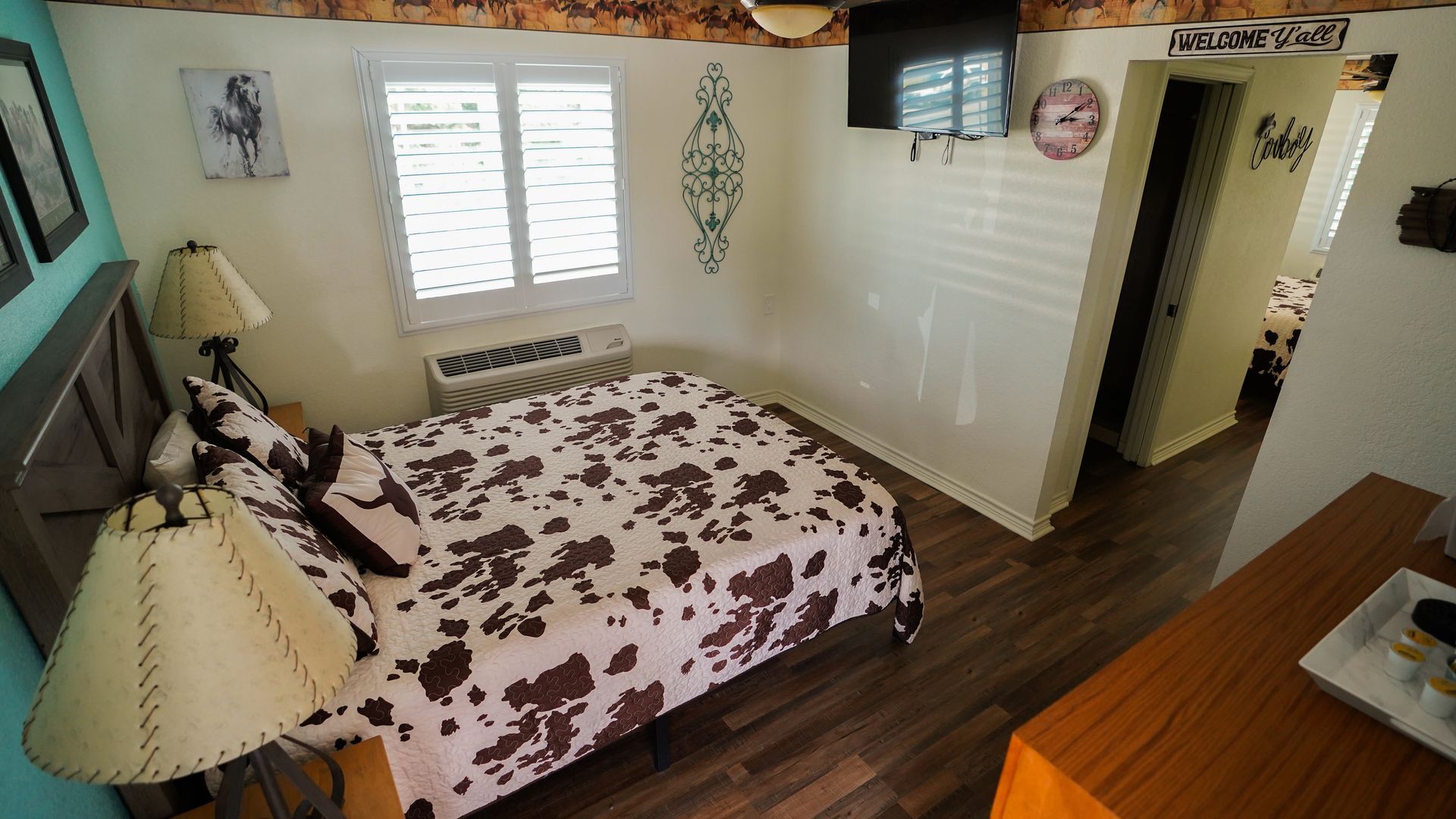 Bedroom with a cow-print comforter, wooden furniture, and a doorway to a bathroom.