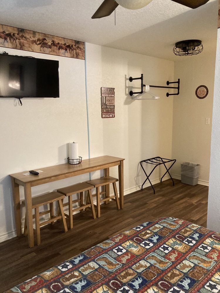 Small hotel room with a TV, table, and bed.