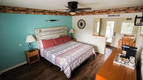 Bedroom with a king bed, turquoise wall, wooden furniture, and western-themed decor.