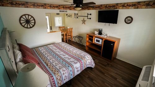 Small motel room with bed, TV, microwave, and a small table and chairs.
