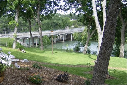 Lush green landscape with a bridge spanning a river. Trees frame the scene.