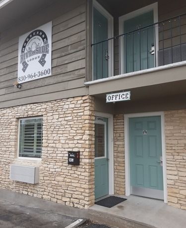 Exterior of Riverside Lodge with an office. Light brown brick and teal doors.