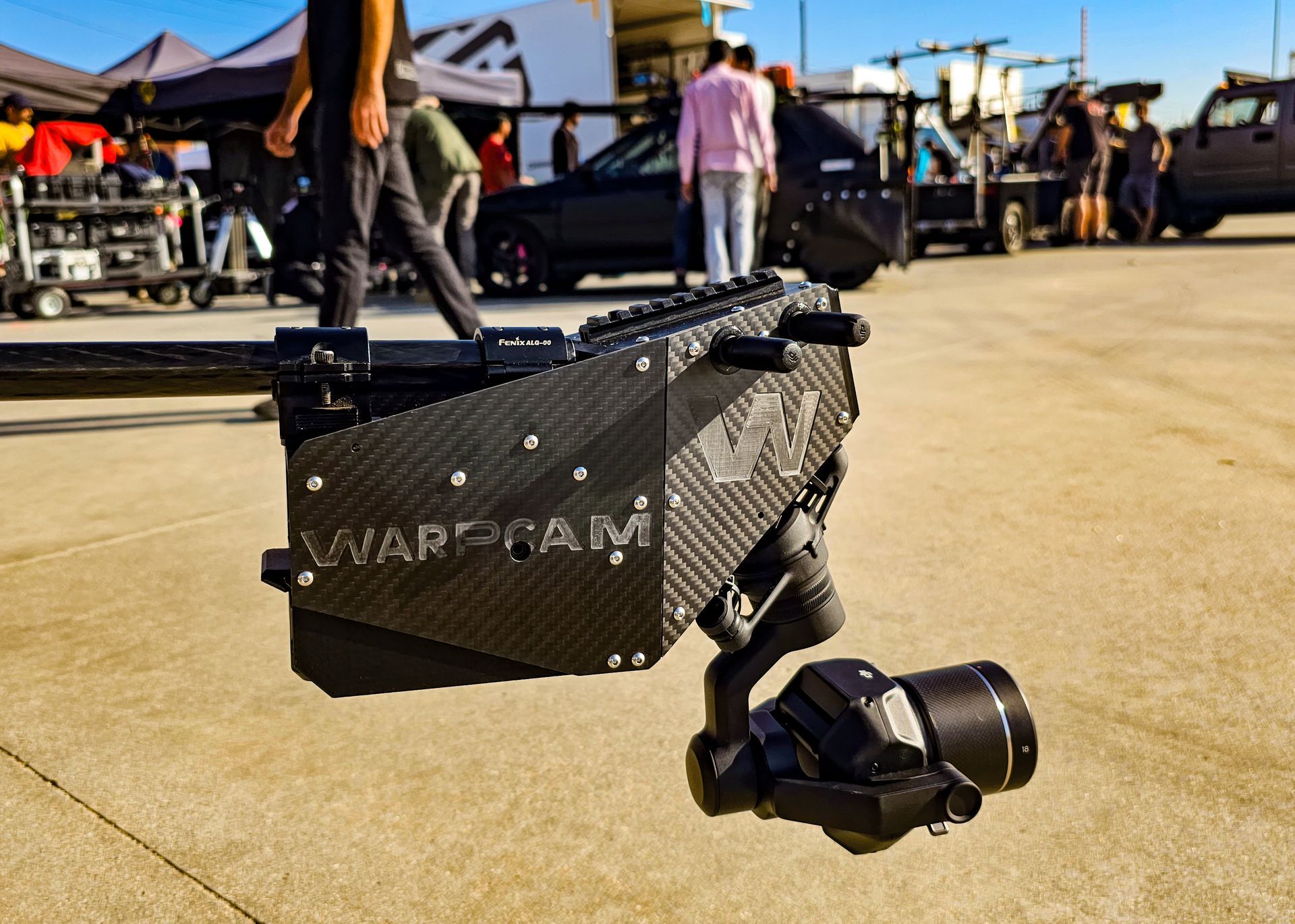 The WarpCam® system mounted on a complex rig, capturing a high-speed action sequence on a bustling movie set, with crew members in the background focused on the shoot.