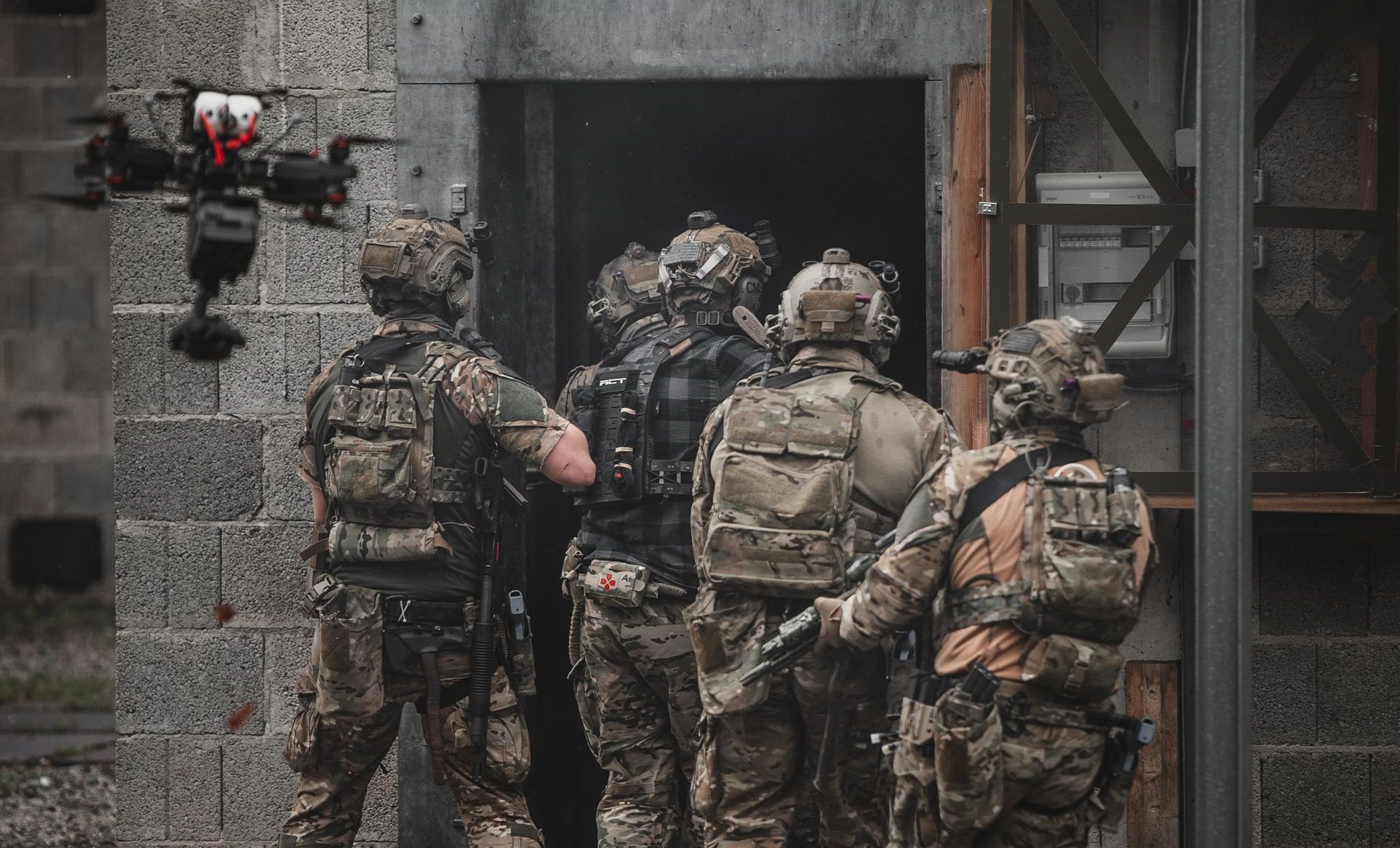 Image of a group of tactical operators entering a house, with the main focus on a cutting-edge WarpCam® mounted on an FPV drone, actively filming the operation.