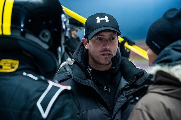 Over the shoulder portrait of action director and stunt coordinator Ferdi Fischer on a snowy Dunlop commercial set, facing two precision drivers as he briefs them on the next driving sequence in a cold winter landscape.